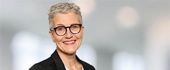 Blonde woman with very short hair and round glasses