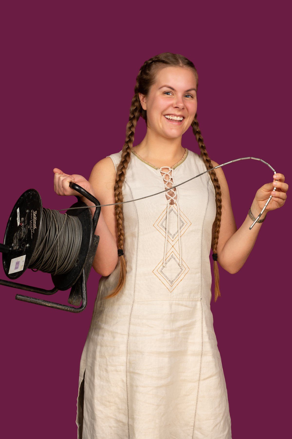 Emely in a dress holding a cable reel