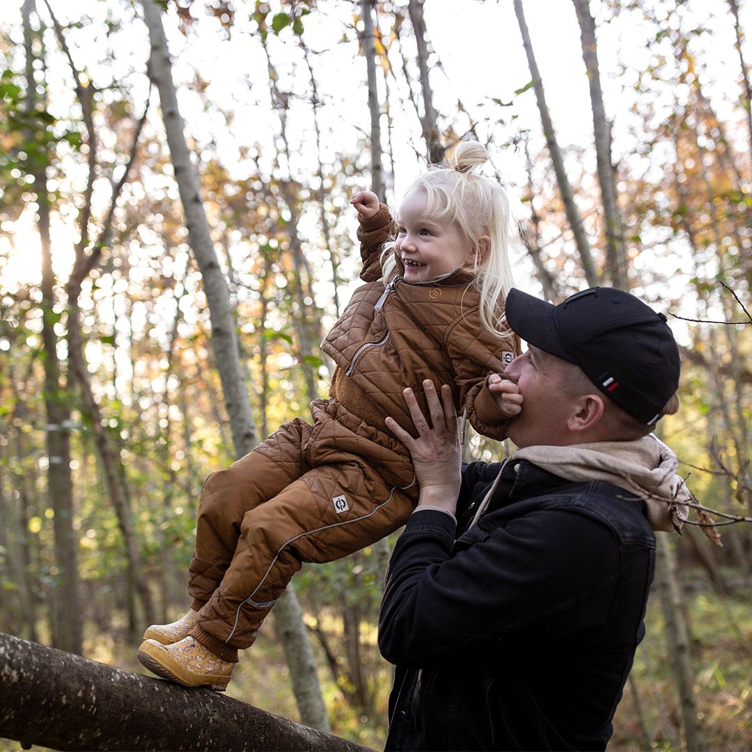 Father holding his daughter on a log in a forest