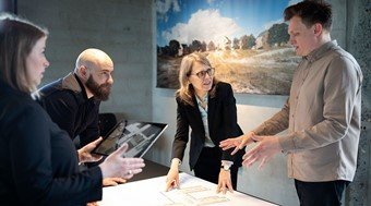 4 Arkitema-kolleger i møde over et bord med arkitekttegninger