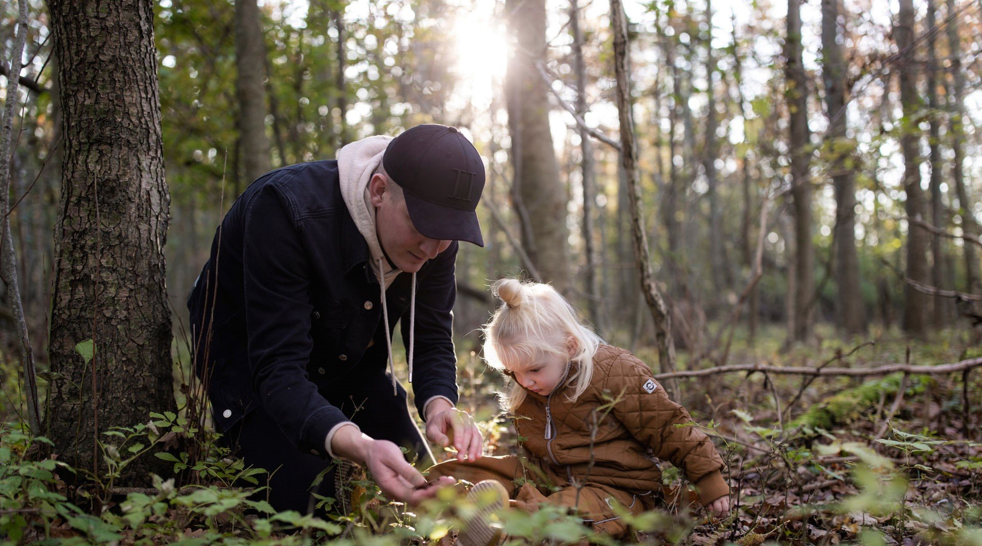 man is playing with a child in the forest