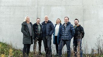 Seks menn og kvinnelige ingeniører fra Trodheim står ved siden av en bygning